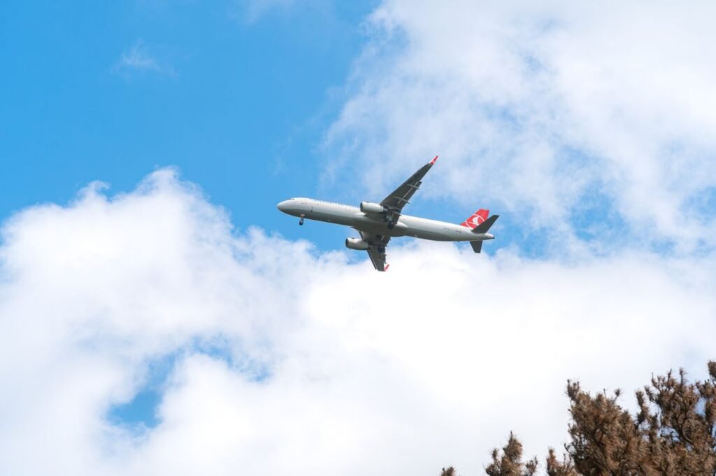 A commercial airplane glides through a clear blue sky with scattered clouds, capturing the essence of aviation travel.